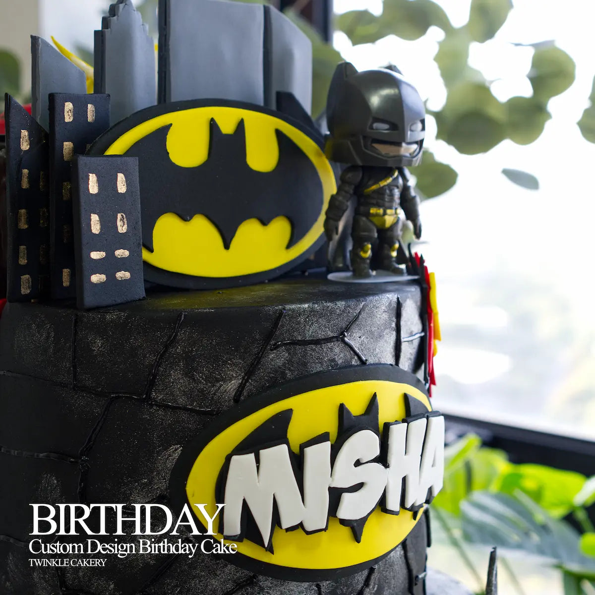 Cartoon version plastic toy toppers of Batman and The Flash on top of a grand birthday cake.