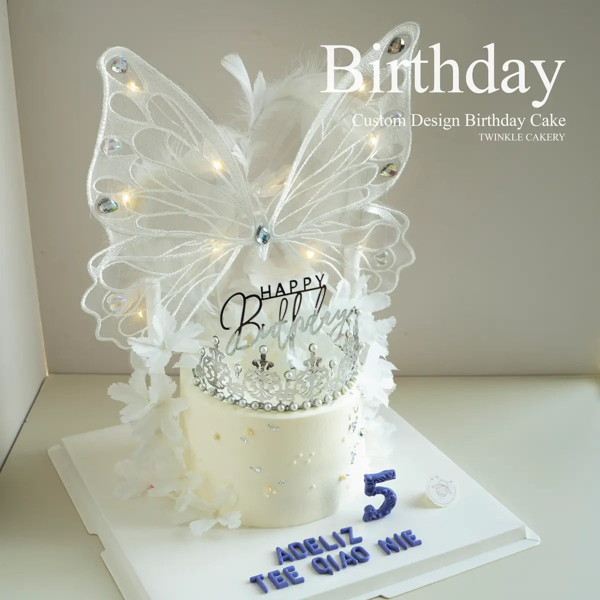 Close-up of glowing LED butterfly topper on white romantic cake - magical effect. Selangor delivery