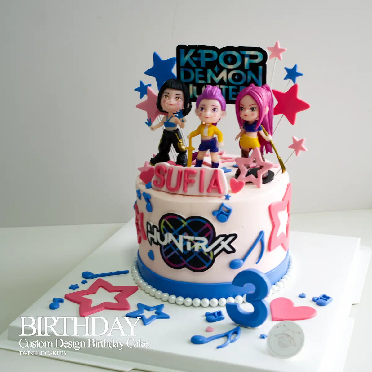 Detailed character toppers of Rumi, Mira, and Zoey from K-Pop Demon Hunters on a birthday cake.