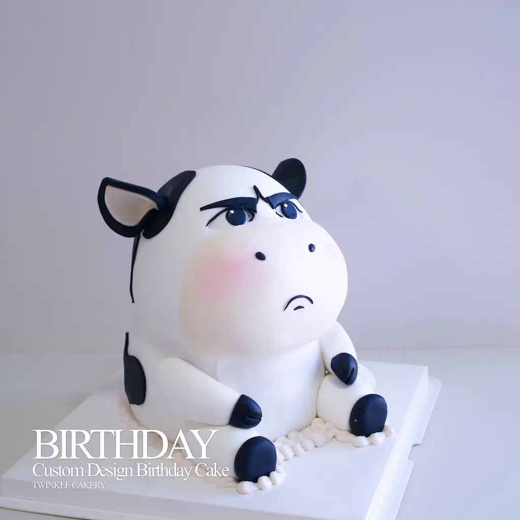 Top-down view of 3D edible fondant cow head and ear on a white frosted cake. By Twinkle Cakery in Selangor & KL