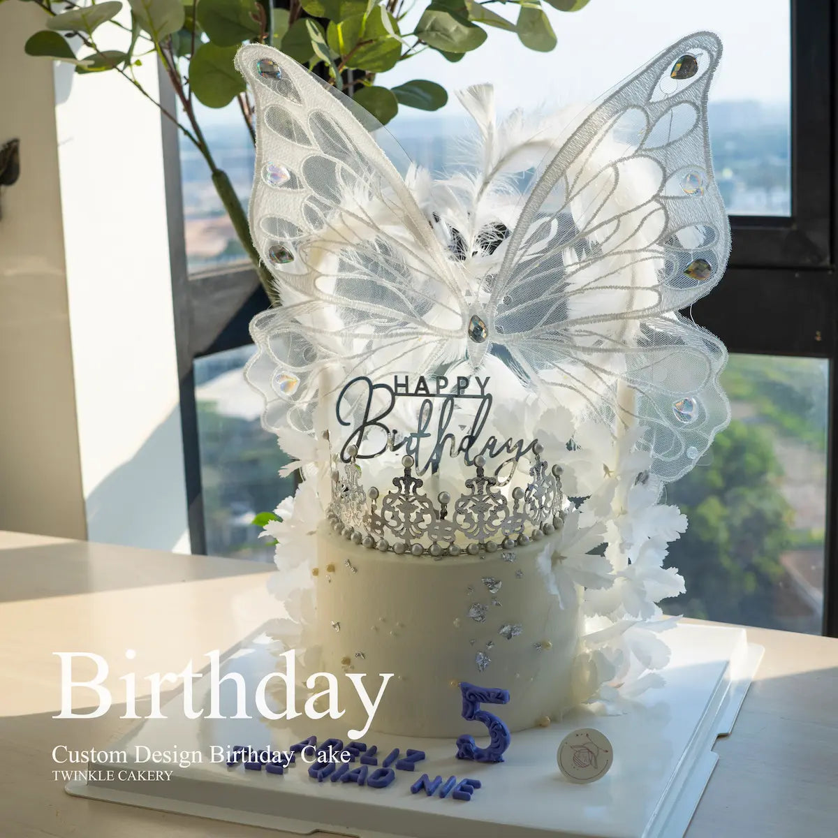 Elegant white butterfly cake with silver crown and ball decorations - daytime view. KL Delivery